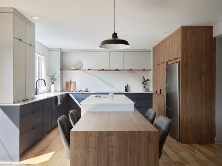 Contemporary open-concept kitchen with natural wood and white counters.