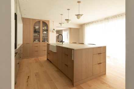 Cuisine aire ouverte minimaliste avec bois clair et luminaires modernes.