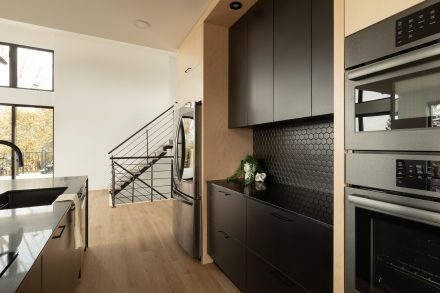 Modern open-concept kitchen with matte black and light wood.